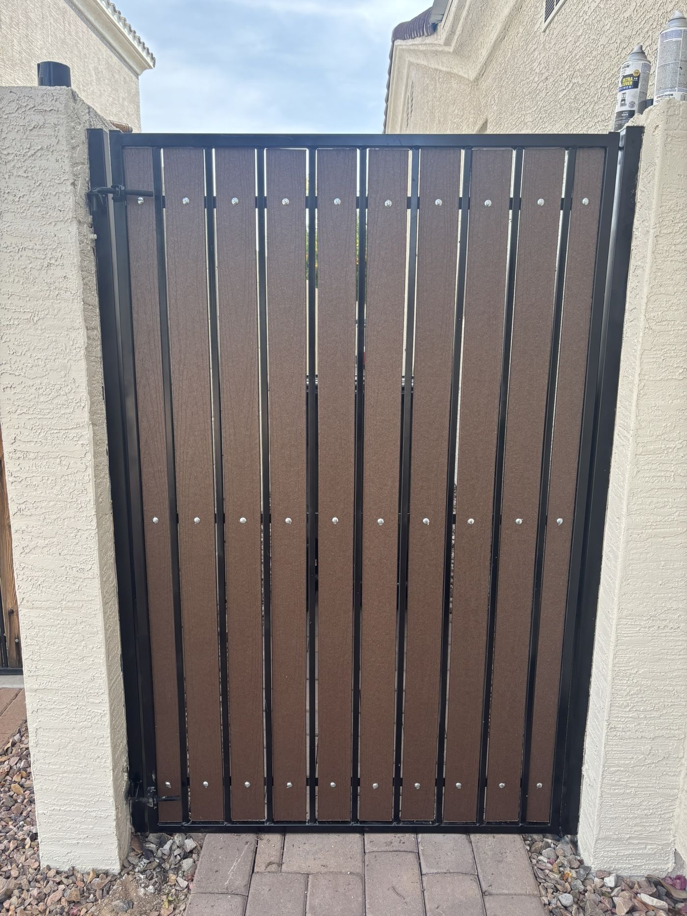 Gate after refurbishment with dark brown slats, glossy black frame, and new bolts