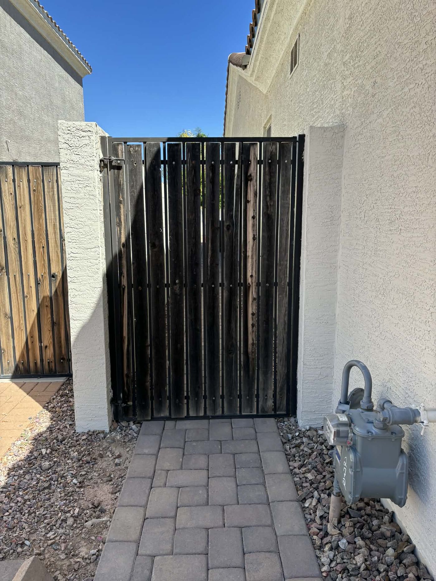 Gate with blackened, weather-worn wood slats before refurbishment